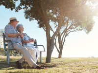 Old couple with a cane sitting at the park and enjoyying the view